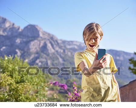Picture - Boy making face for selfie on smartphone, Majorca, Spain. Fotosearch