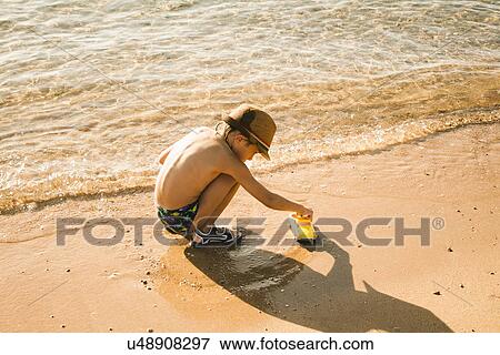 Boy playing by seaside View Large Photo Image Stock Photo - Boy playing by seaside. Fotosearch