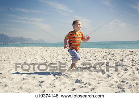 Stock Photograph - Boy running on beach, Cape Town, Western Cape, South Africa. Fotosearch