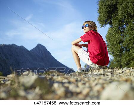 Stock Photo - Boy sitting gazing at mountains, Majorca, Spain. Fotosearch