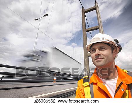 Stock Image - Bridge worker close to traffic on suspension bridge. The Humber Bridge, UK was built in 1981 and at the time was the world's largest single-span suspension bridge. Fotosearch