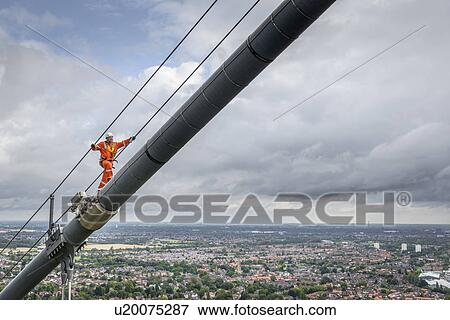 Stock Photo - Bridge worker walking on cable of suspension bridge. The Humber Bridge, UK was built in 1981 and at the time was the world's largest single-span suspension bridge. Fotosearch