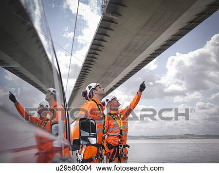 Picture - Bridge workers and support truck under suspension bridge. The Humber Bridge, UK was built in 1981 and at the time was the world's largest single-span suspension bridge. Fotosearch