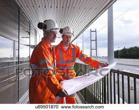 Stock Image - Bridge workers inspecting engineering plans for suspension bridge. The Humber Bridge, UK was built in 1981 and at the time was the world's largest single-span suspension bridge. Fotosearch