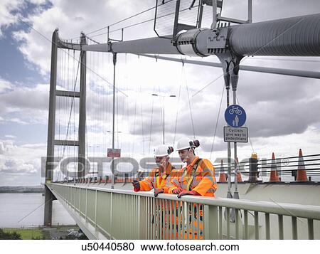 Stock Image - Bridge workers on parapet of suspension bridge. The Humber Bridge, UK was built in 1981 and at the time was the world's largest single-span suspension bridge. Fotosearch