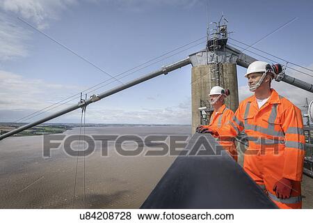 Stock Photo - Bridge workers on top of suspension bridge. The Humber Bridge, UK was built in 1981 and at the time was the world's largest single-span suspension bridge. Fotosearch