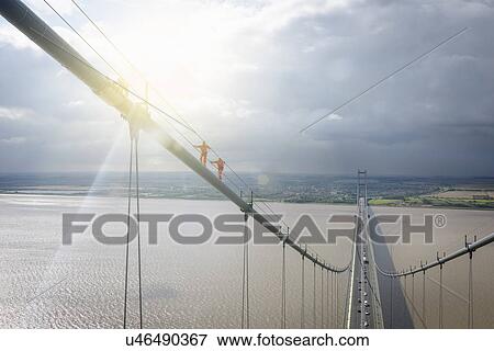 Bridge workers walking on cable of suspension bridge under bright sunlight. The Humber Bridge, UK was built in 1981 and at the time was the world's largest single-span suspension bridge View Large Photo Image Stock Photo - Bridge workers walking on cable of suspension bridge under bright sunlight. The Humber Bridge, UK was built in 1981 and at the time was the world's largest single-span suspension bridge. Fotosearch