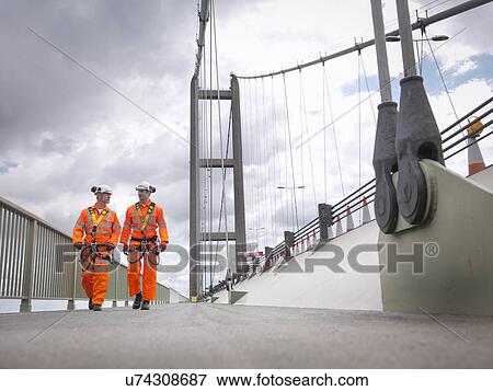 Stock Photo - Bridge workers walking on parapet of suspension bridge. The Humber Bridge, UK was built in 1981 and at the time was the world's largest single-span suspension bridge. Fotosearch