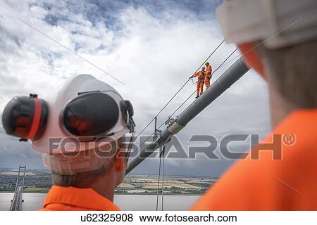 Stock Photo - Bridge workers working on cable of suspension bridge. The Humber Bridge, UK was built in 1981 and at the time was the world's largest single-span suspension bridge. Fotosearch