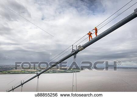Stock Photograph - Bridge workers working on cable of suspension bridge. The Humber Bridge, UK was built in 1981 and at the time was the world's largest single-span suspension bridge. Fotosearch