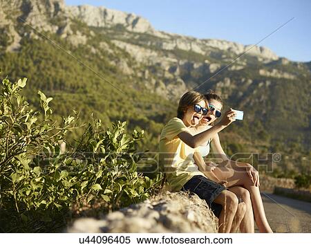 Stock Photography - Brother and sister making faces for selfie on smartphone, Majorca, Spain. Fotosearch