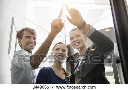Stock Photo - Businessman and businesswomen looking and pointing at light. Fotosearch