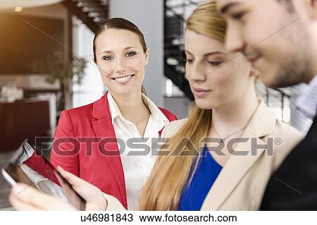 Stock Image - Businessman and businesswomen sharing information on digital tablet. Fotosearch