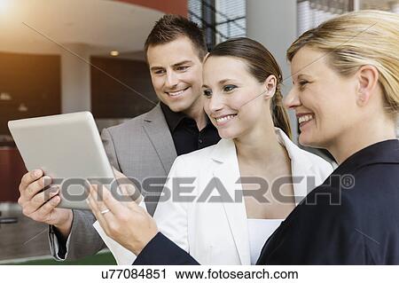 Stock Image - Businessman and businesswomen sharing information on digital tablet. Fotosearch