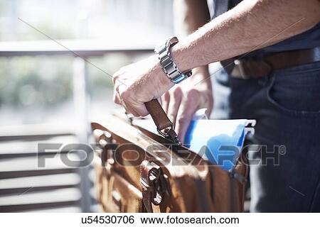 Stock Photograph - Businessman putting paperwork in briefcase. Fotosearch