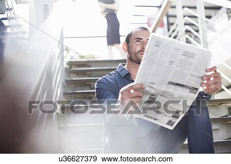 Stock Photo - Businessman reading newspapers on staircase. Fotosearch