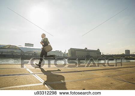Businessman running along waterfront View Large Photo Image Stock Photo - Businessman running along waterfront. Fotosearch