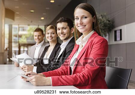 Stock Image - Businessmen and businesswomen with digital tablet at meeting table. Fotosearch
