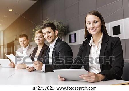 Stock Photography - Businessmen and businesswomen with digital tablet at meeting table. Fotosearch