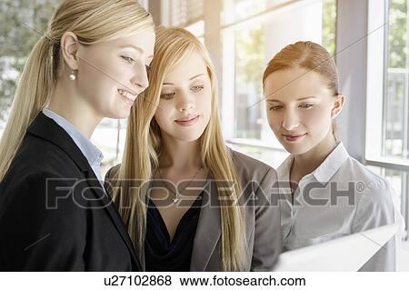 Stock Photo - Businesswomen sharing information on digital tablet. Fotosearch