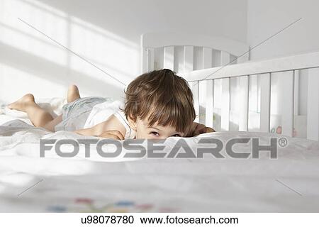Candid portrait of female toddler peeking over bed quilt View Large Photo Image Stock Image - Candid portrait of female toddler peeking over bed quilt. Fotosearch