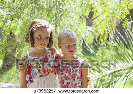 Candid portrait of two girls looking away in garden View Large Photo Image Stock Photo - Candid portrait of two girls looking away in garden. Fotosearch