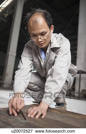 Stock Photo - Carpenter checking quality of wood plank in factory, Jiangsu, China. Fotosearch