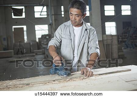 Stock Photo - Carpenter cutting wood plank in factory, Jiangsu, China. Fotosearch