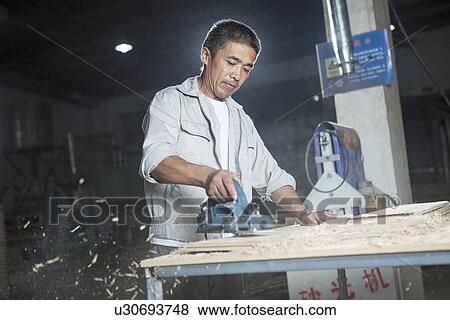 Carpenter cutting wood plank in factory, Jiangsu, China View Large Photo Image Stock Photo - Carpenter cutting wood plank in factory, Jiangsu, China. Fotosearch