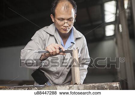 Stock Photo - Carpenter measuring wood plank with vernier caliper in factory, Jiangsu, China. Fotosearch
