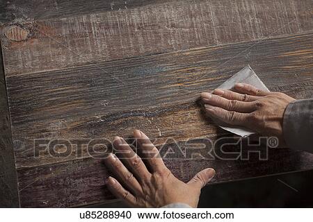 Stock Image - Carpenter smoothing surface of wood plank with sandpaper in factory, Jiangsu, China. Fotosearch