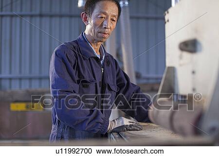 Stock Image - Carpenter working on wood flooring in factory, Jiangsu, China. Fotosearch