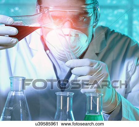 Stock Image - Chemist pouring liquid from beaker into test tube. Fotosearch