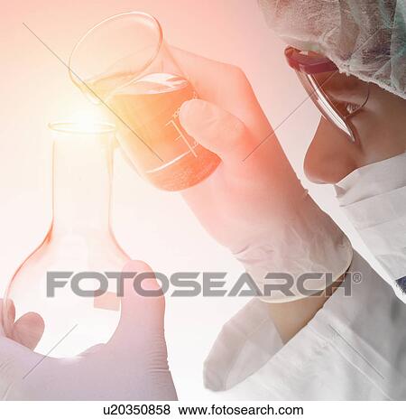 Chemist pouring liquid from beaker into flask View Large Photo Image Stock Photo - Chemist pouring liquid from beaker into flask. Fotosearch