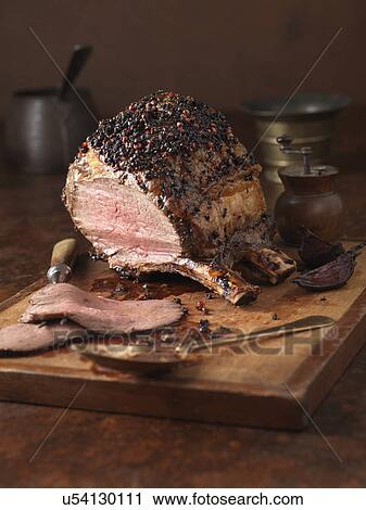 Stock Image - Christmas dinner. Bone in sirloin joint with peppercorn crust and brandy glaze served with roasted potatoes. Fotosearch