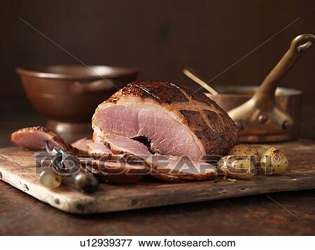 Stock Photo - Christmas dinner. Muscavado sugar baked gammon served with roasted new potatoes and herbs. Fotosearch