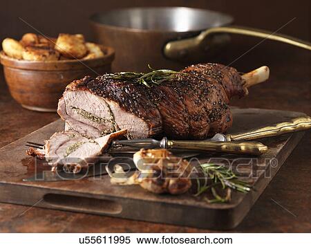 Stock Photography - Christmas dinner. Roasted rosemary and garlic leg of lamb and roast potatoes. Fotosearch