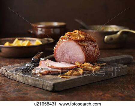 Stock Image - Christmas dinner. Small roasted orange marmalade gammon on chopping board. Fotosearch