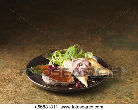 Stock Image - Christmas snack of duck liver pate with armagnac & cranberries. Shredded spring onion, bay leaf and mixed green salad leaves. Fotosearch