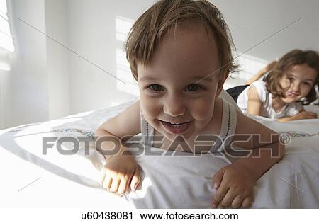 Close up candid portrait of female toddler and cousin lying on bed View Large Photo Image Stock Image - Close up candid portrait of female toddler and cousin lying on bed. Fotosearch
