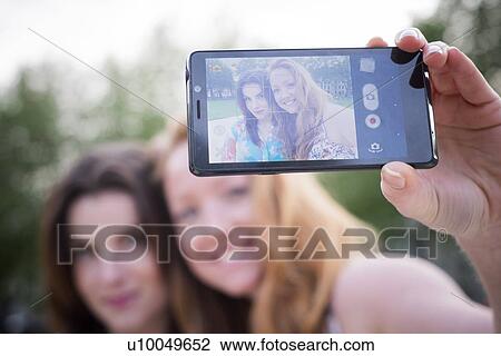 Close up of two young female friends taking selfie on smartphone in park View Large Photo Image Stock Image - Close up of two young female friends taking selfie on smartphone in park. Fotosearch