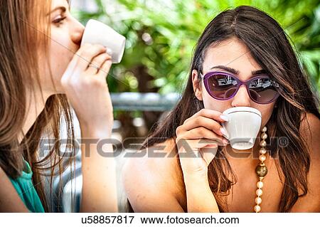 Close up of two young female friends drinking espresso at sidewalk cafe, Cagliari, Sardinia, Italy View Large Photo Image Stock Photo - Close up of two young female friends drinking espresso at sidewalk cafe, Cagliari, Sardinia, Italy. Fotosearch