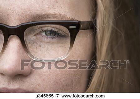 Stock Photo - Close-up of young woman with freckles wearing eye glasses. Fotosearch