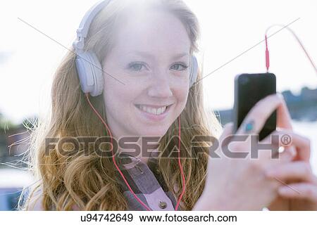 Close up portrait of young woman listening to music on headphones on street View Large Photo Image Stock Photo - Close up portrait of young woman listening to music on headphones on street. Fotosearch