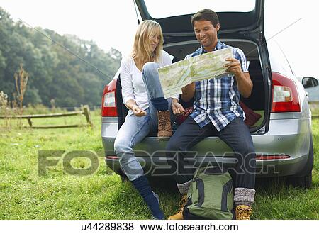 Stock Photo - Couple at rear of car map reading preparing for walk. Fotosearch
