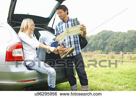 Couple at rear of car map reading preparing for walk View Large Photo Image Stock Photograph - Couple at rear of car map reading preparing for walk. Fotosearch