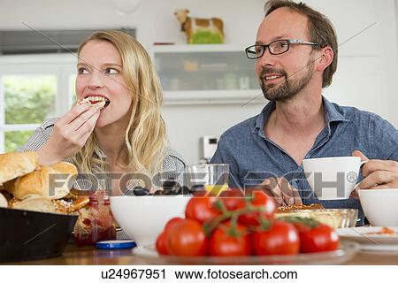 Stock Image - Couple eating at kitchen table. Fotosearch