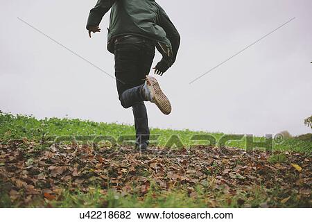 Stock Image - Cropped shot of young man running in field. Fotosearch