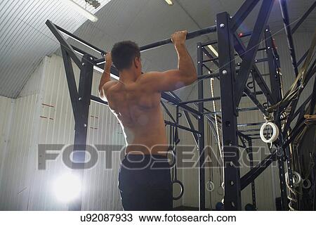 Crossfitter doing pull ups in gym View Large Photo Image Stock Image - Crossfitter doing pull ups in gym. Fotosearch