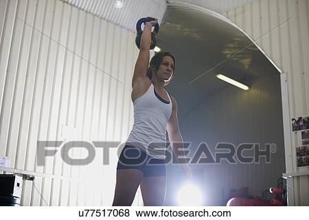 Stock Photo - Crossfitter lifting kettlebell in gym. Fotosearch
